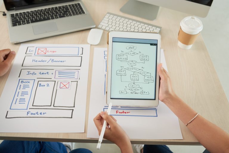 Team designing website layout with flowchart on tablet.