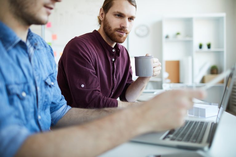 Two men discussing work at laptop