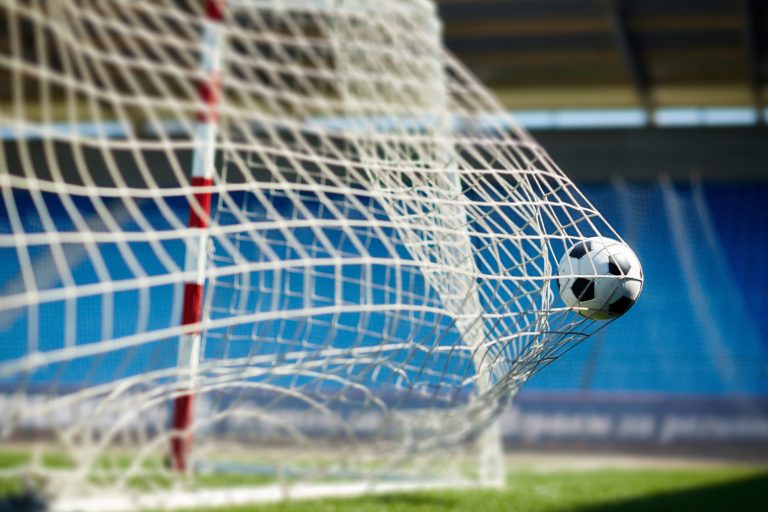 Soccer ball hitting goal net in stadium